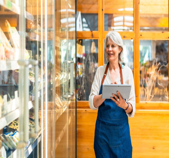 Store staff member in an apron checking records on a tablet